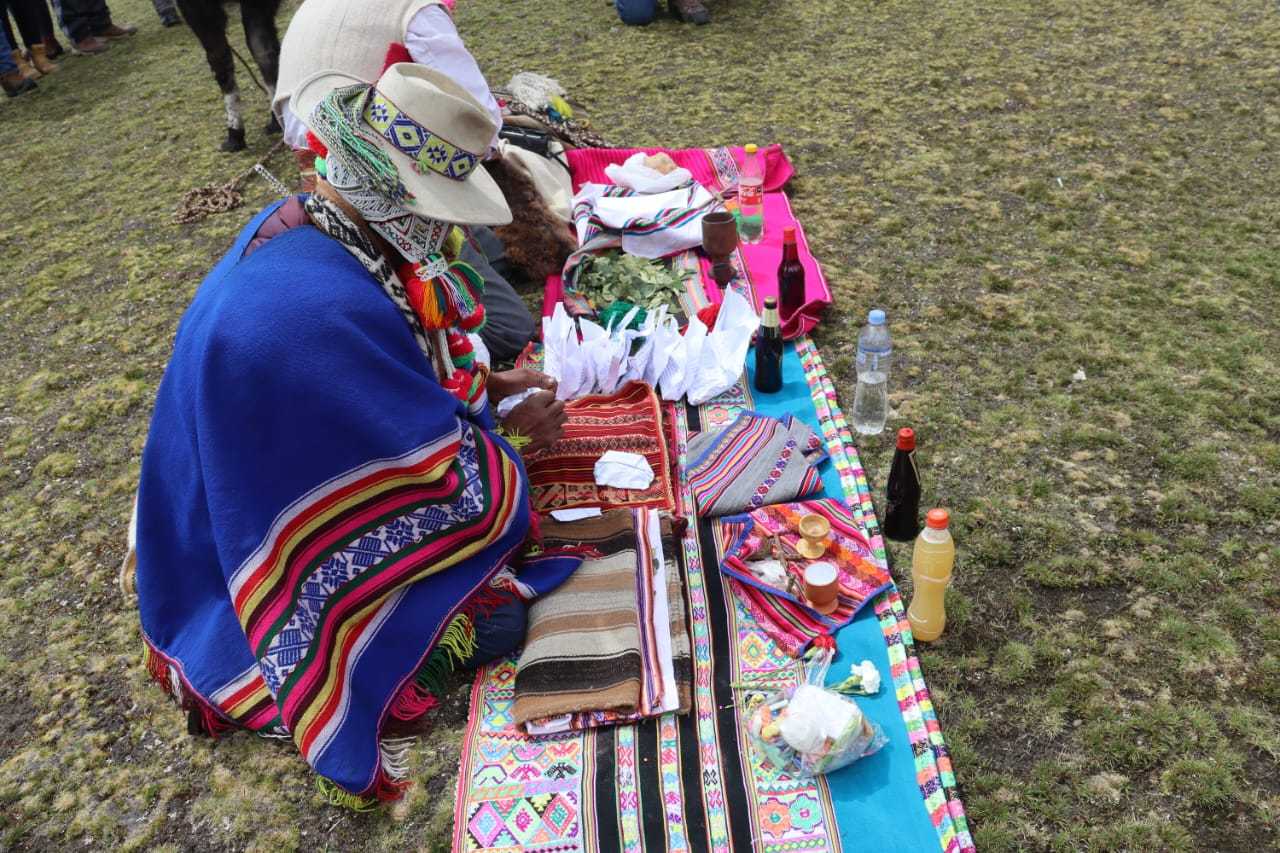 Sacerdote andino realizando un Pago a la Tierra con ofrendas de hojas de coca y maíz en un altar sagrado